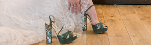 Woman putting on designer green wedding shoes from Freya Rose London