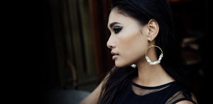 Woman wearing statement baroque pearl and seed pearl large gold hoop earrings