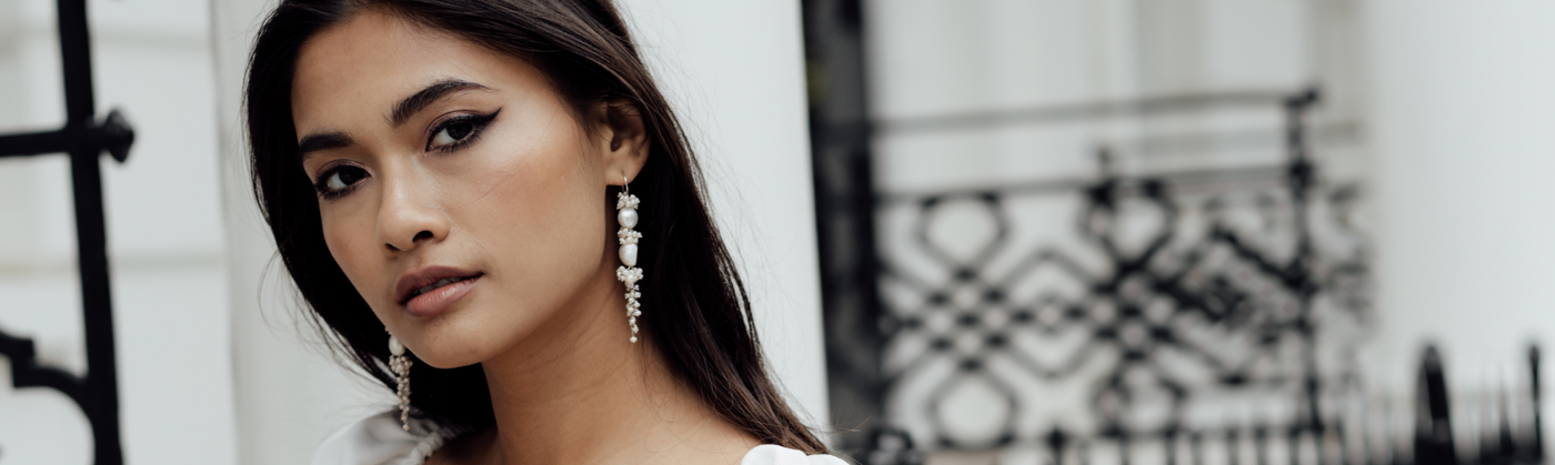 Elegant woman wearing designer pearl earrings from Freya Rose London